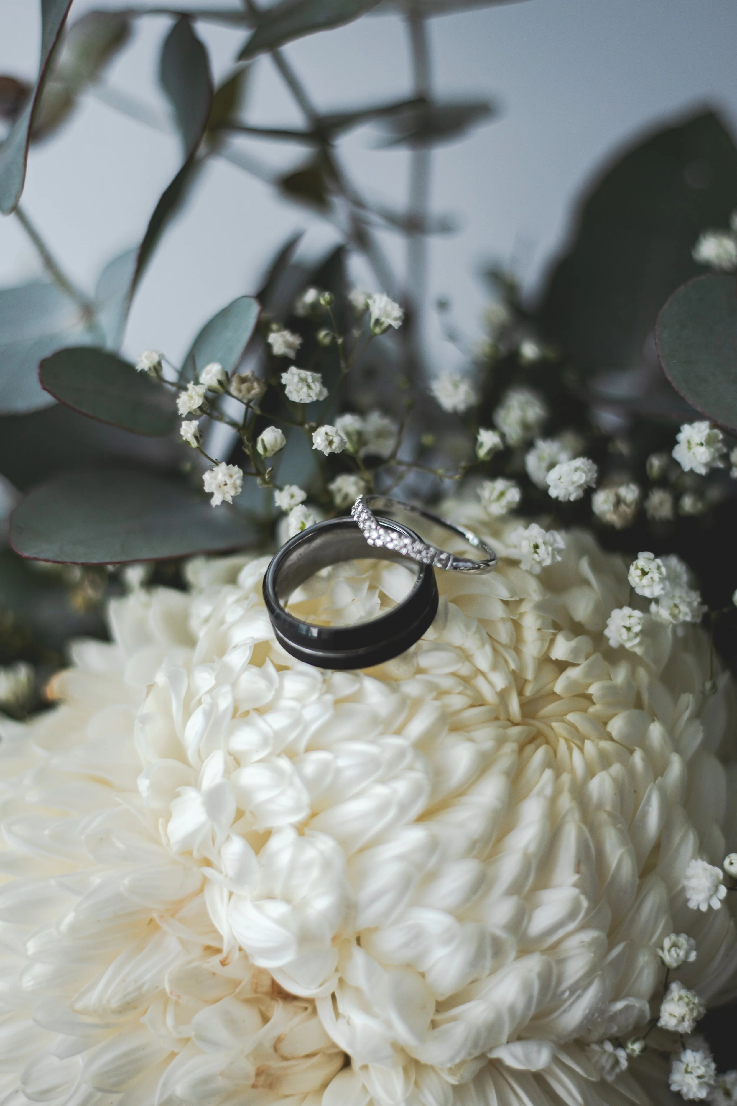 Close up detail of wedding rings sitting on bouquet of flowers. 