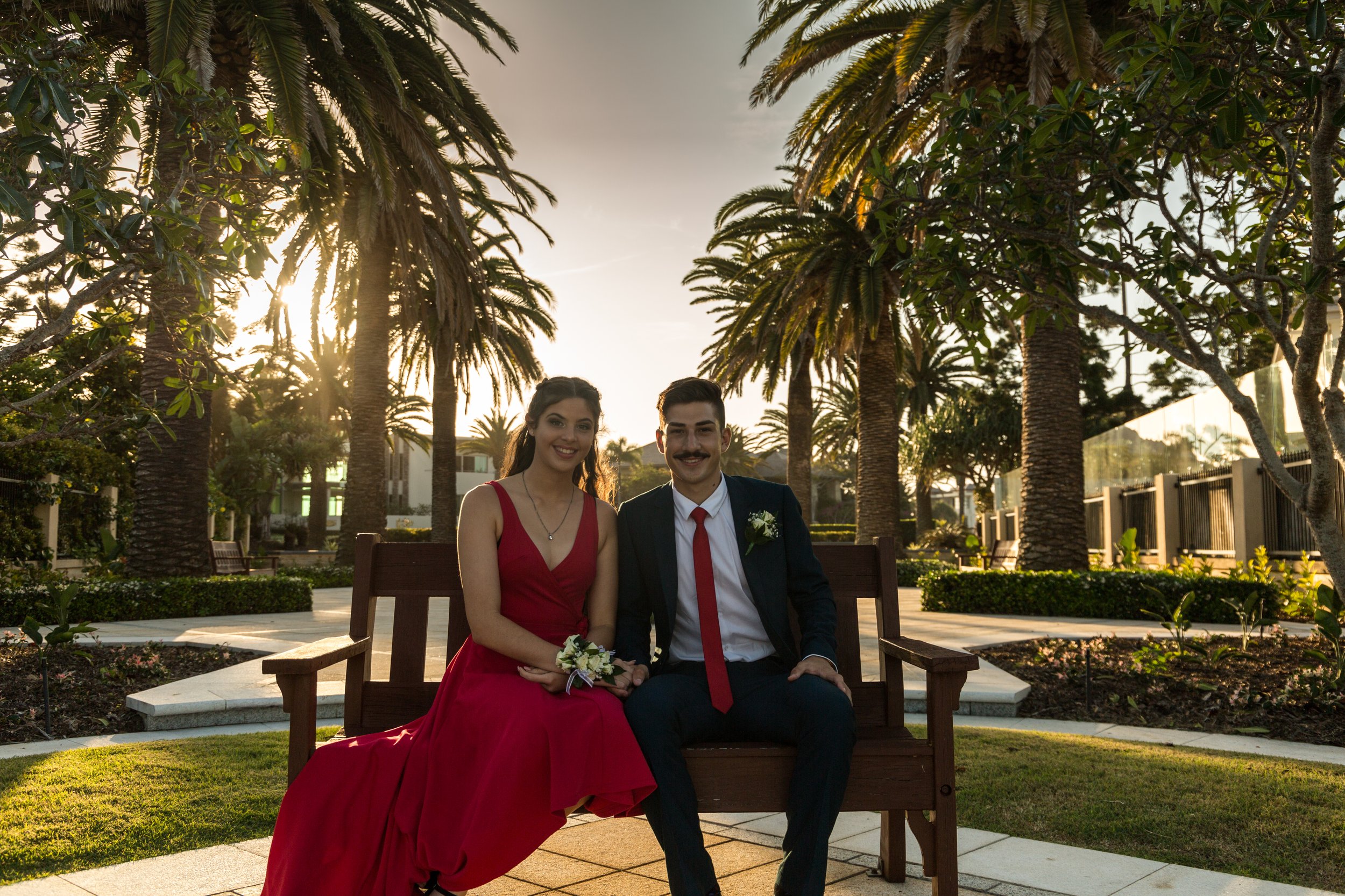Couple siting on bench in picturesque garden at Sovereign Island with a golden sunset.