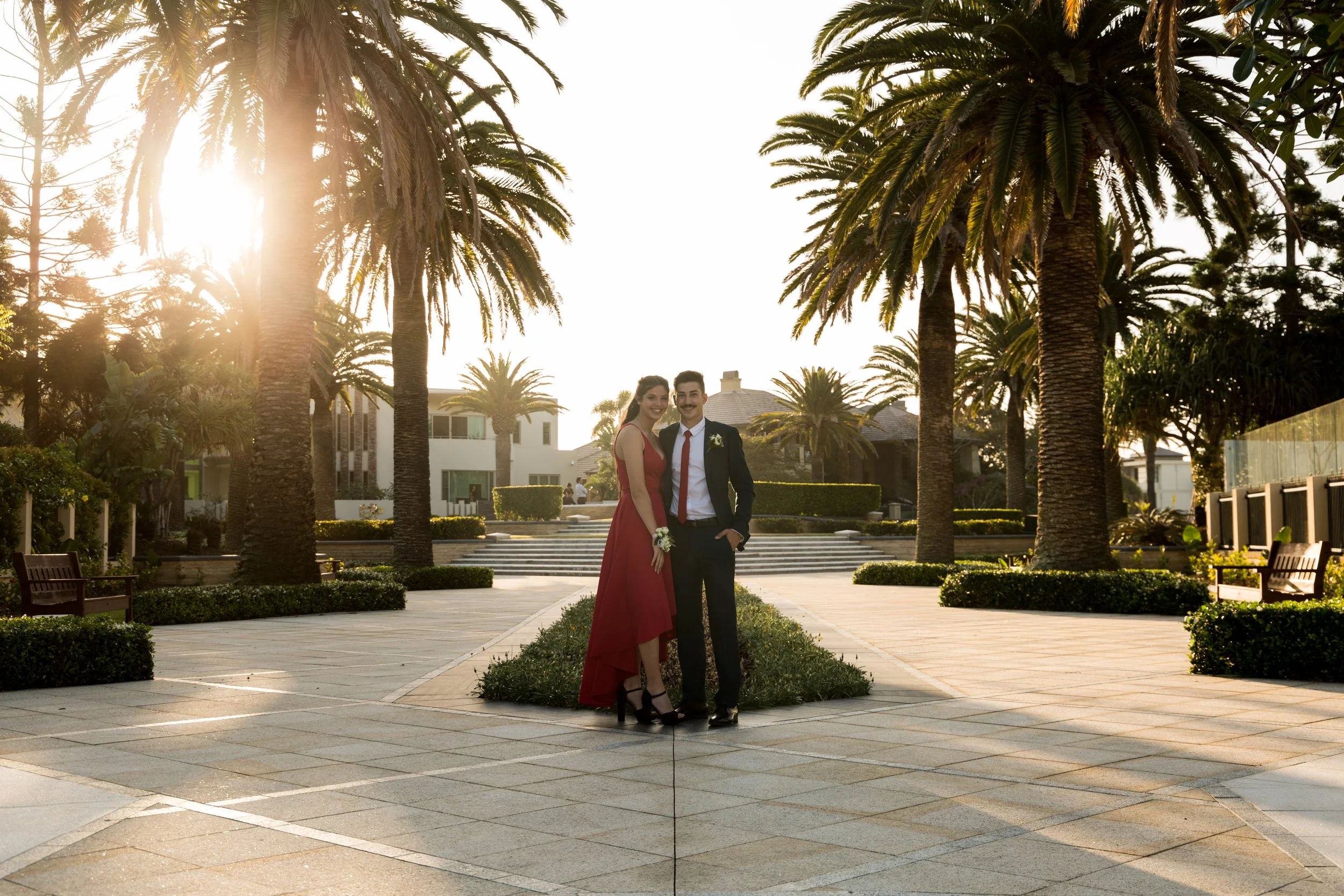 Couple stand in picturesque garden at Sovereign Island during golden sunset.