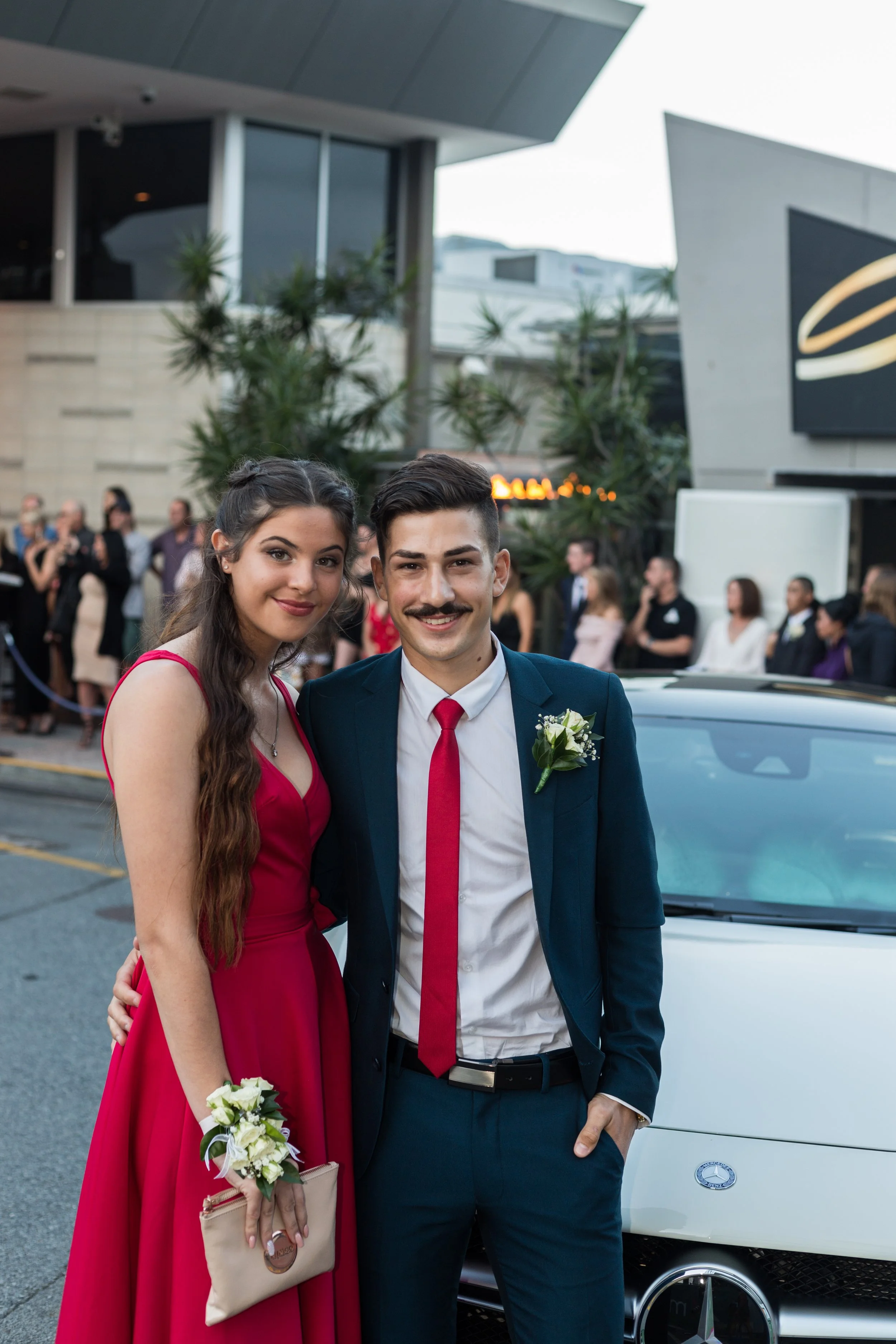 Formal students stand in front of car on arrival at the formal location.