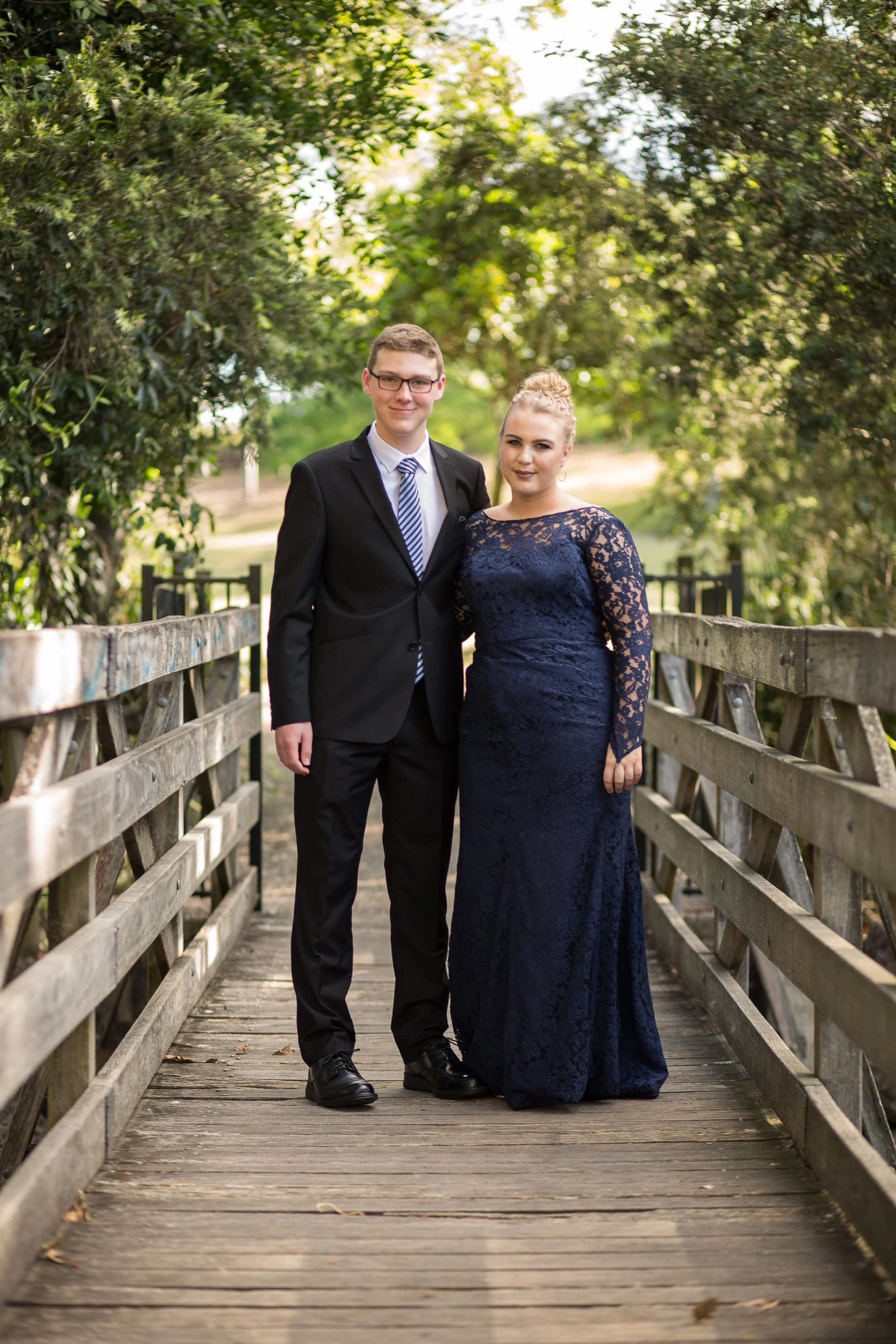 Couple portrait for school formal couple on timber bridge with stunning natural golden sunlight.