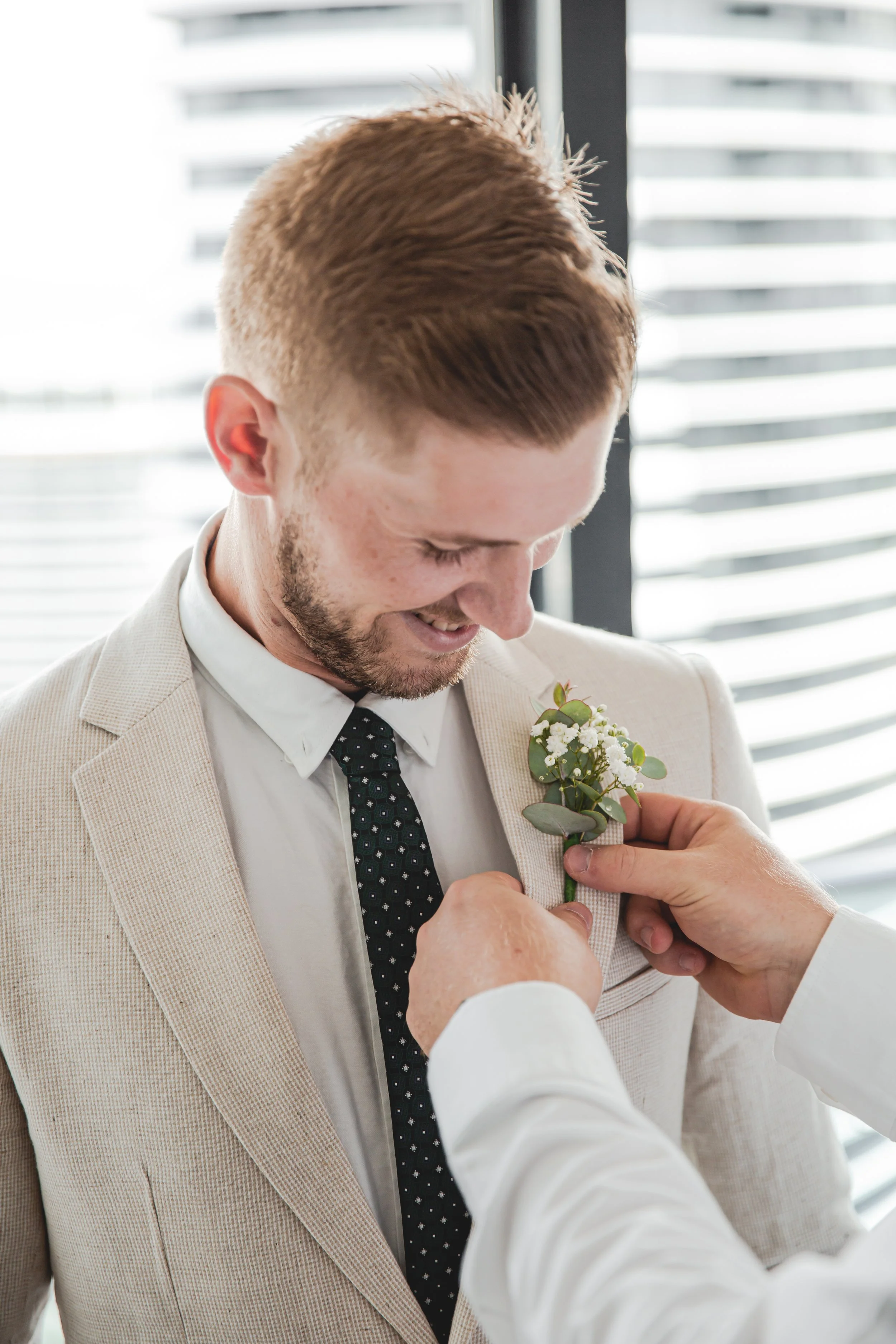 Portrait of male getting boutonniere on jacket at Peppers Broadbeach for a wedding.  