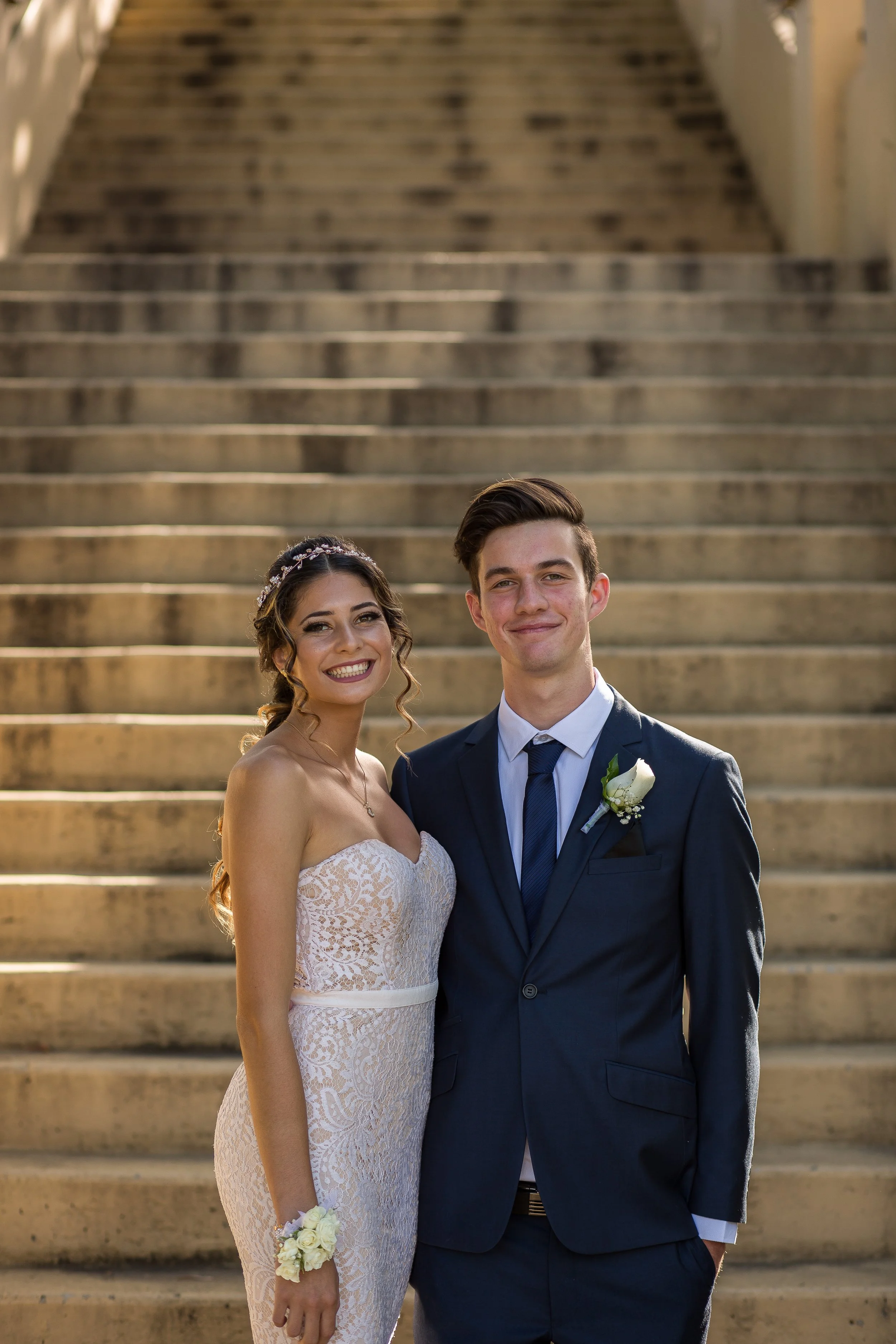 Couples student formal portrait at bottom of stairs with natural golden light.