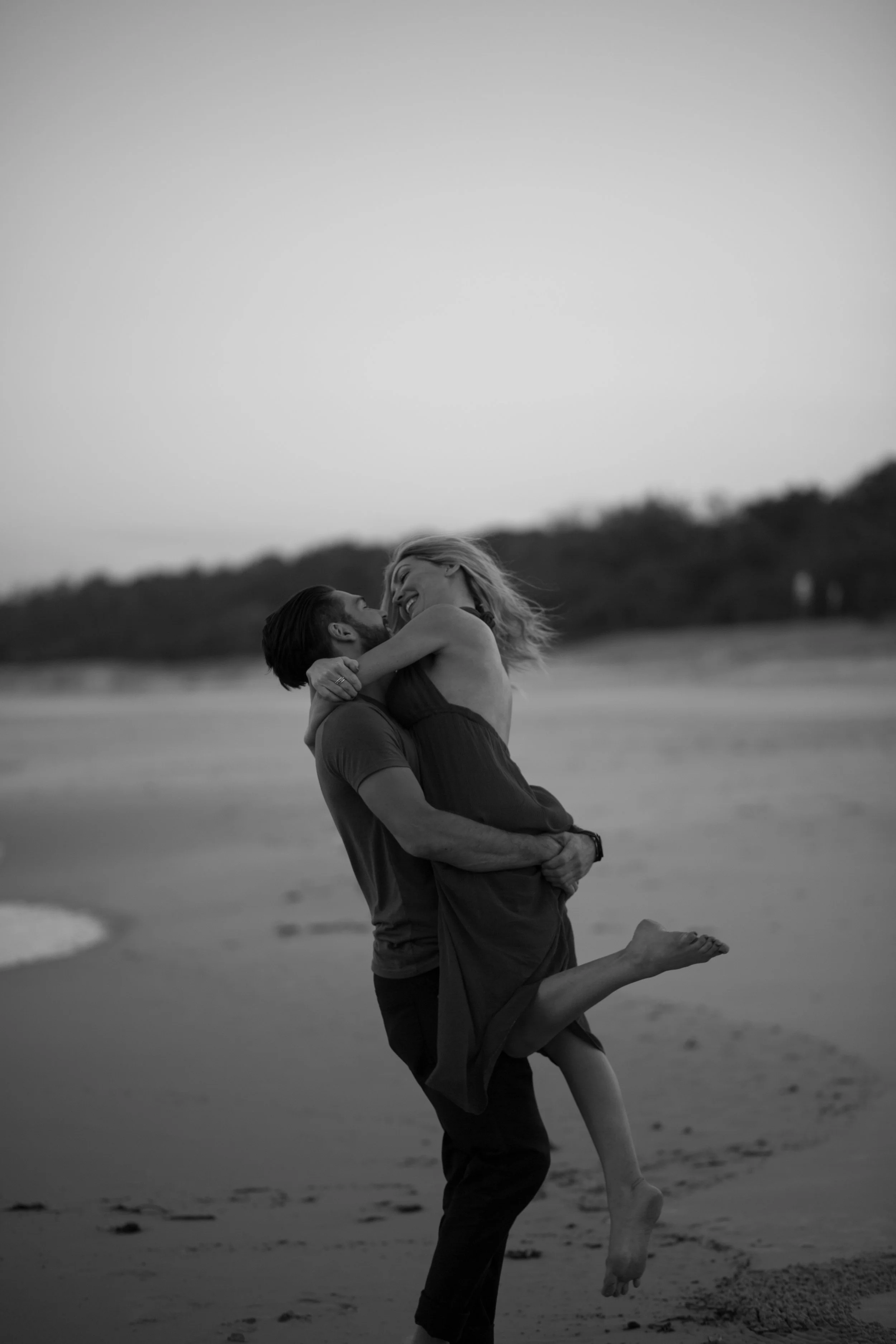 Couple hugging and spinning on the beach at Fingal Beach. 