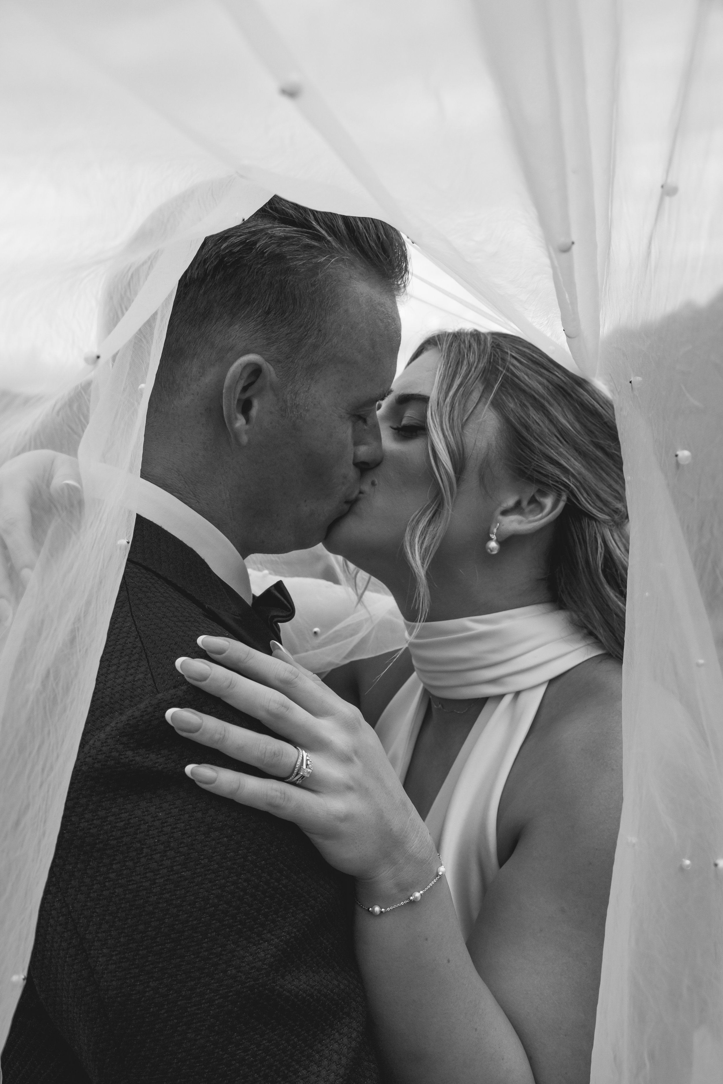 Newly weds under veil sharing a kiss at their wedding on top of the hill at Selah Valley Estate.