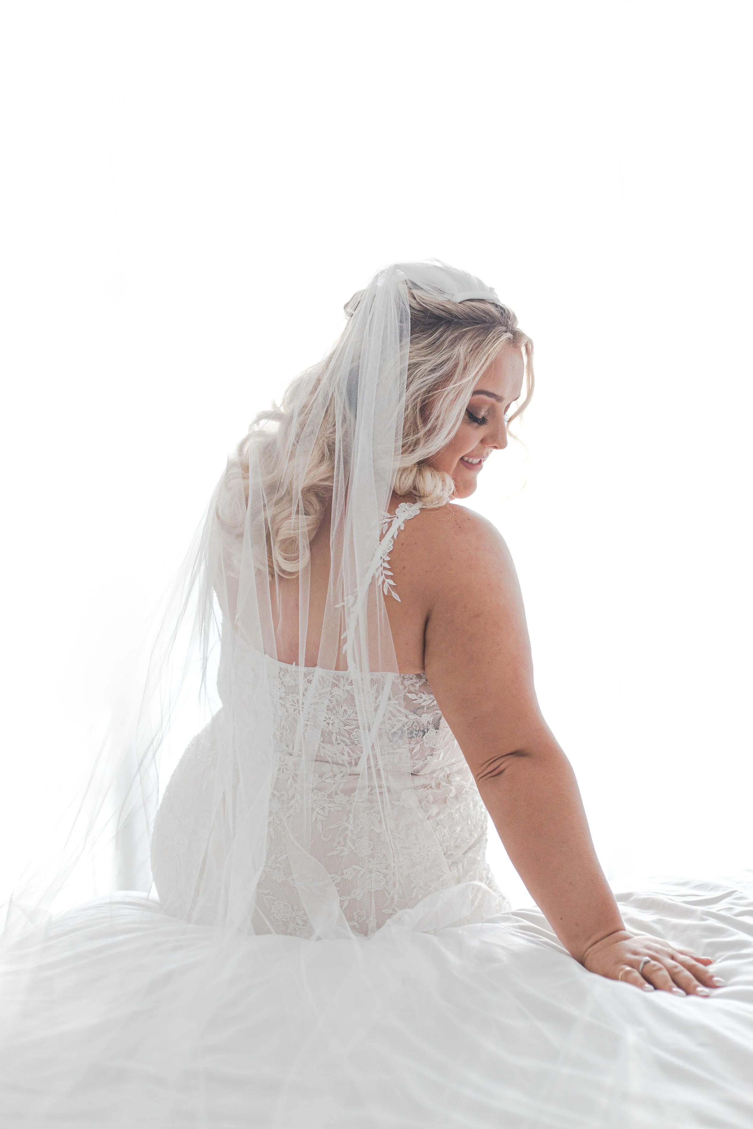 Bride sitting on bed in wedding dress with natural sunlight through big window at Peppers Broadbeach.