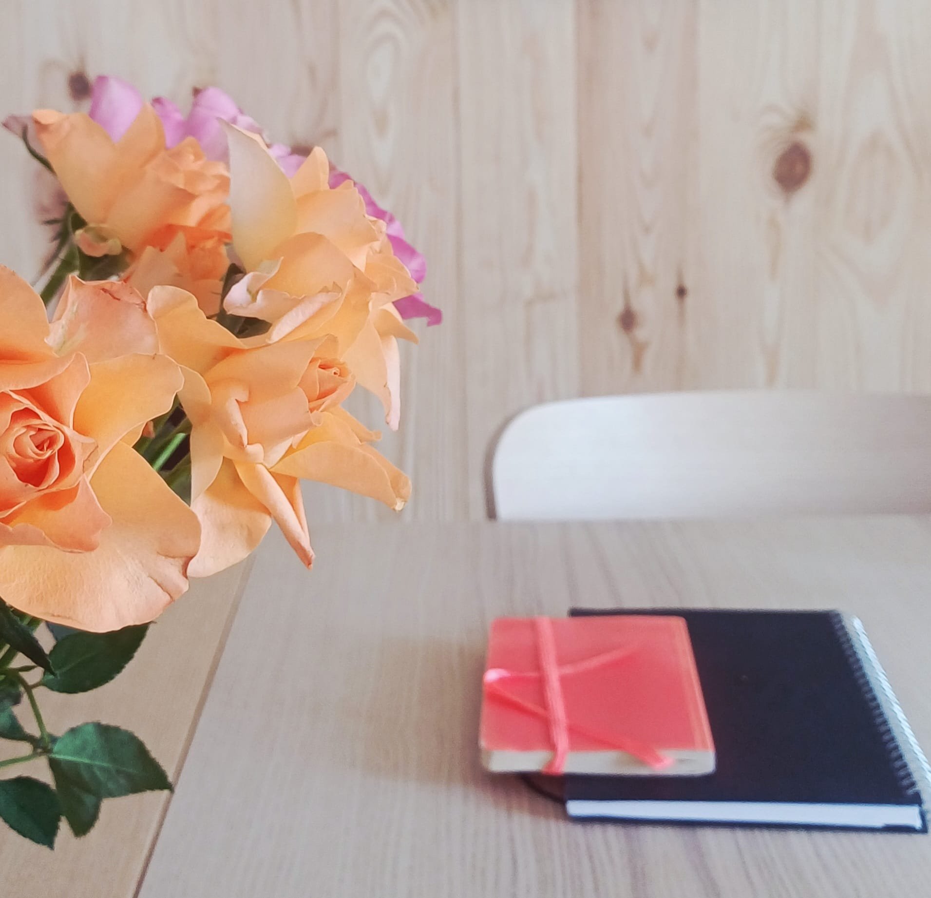 Fleurs de roses orange et violet, et deux boîtes à chaussures rouges et noires sur une table en bois.