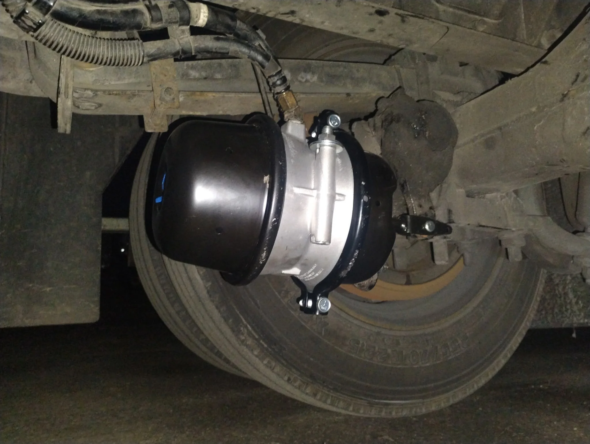 Close-up of a large vehicle tire showing a wheel, suspension, and some mechanical parts.
