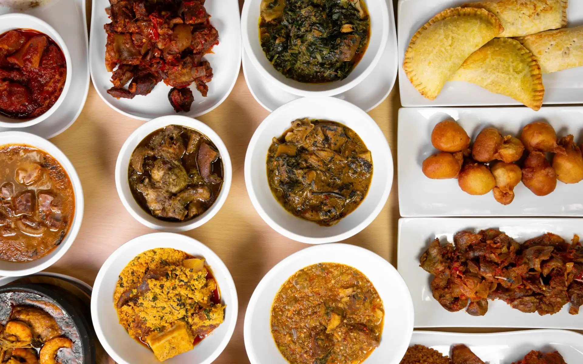 Assorted traditional Indian dishes served in white bowls and plates, including curries, vegetable dishes, and fried snacks.