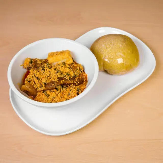 Indian meal with vegetable curry in a bowl and a round bread on a white plate