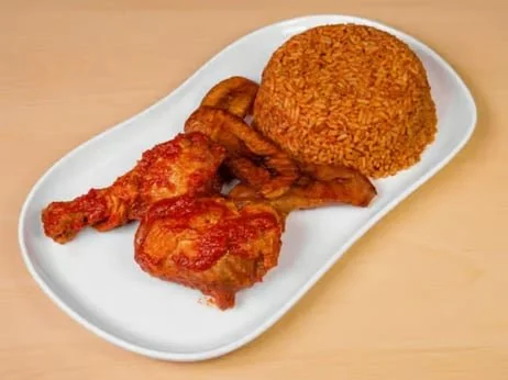 Plate with fried chicken drumstick and wing, a serving of rice, and fried plantains.
