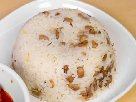 A ball of rice with chopped nuts on top, served on a white dish.