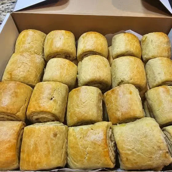 A box of multiple small, golden-brown bread rolls arranged in a grid pattern.