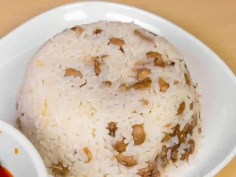 A ball of cooked rice with chickpeas and spices on a white plate.