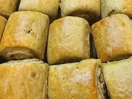 Close-up of several cooked beef or vegetable roll-up pastries arranged on a surface.