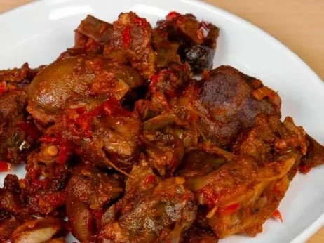 Close-up of a plate of cooked beef stew with vegetables and tomato sauce.
