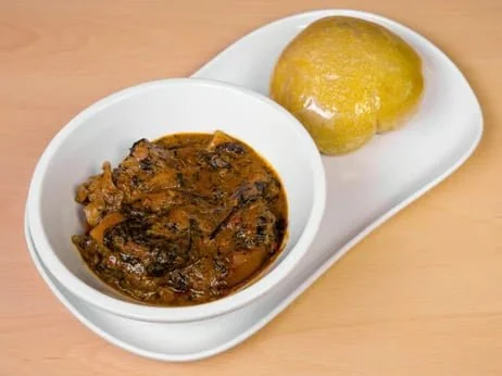 Bowl of beef stew with a piece of bread on a white tray