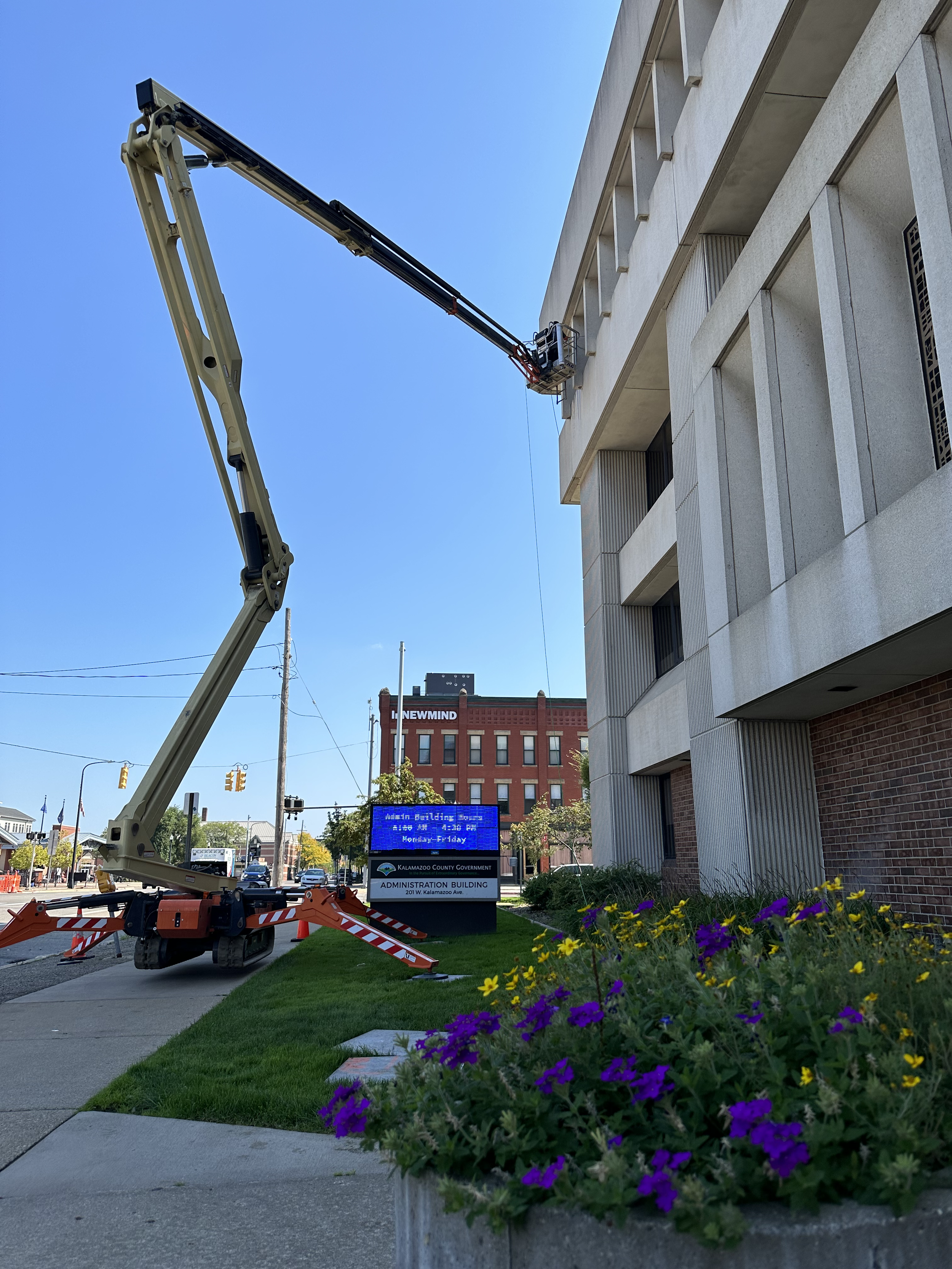Professional window cleaner operating an articulating boom lift, cleaning the windows of a Kalamazoo County government building.