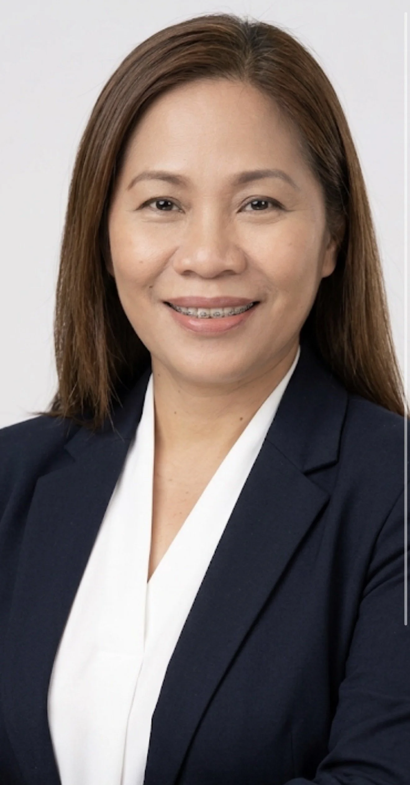 A professional woman with shoulder-length brown hair, wearing a dark blazer and white blouse, smiling at the camera.