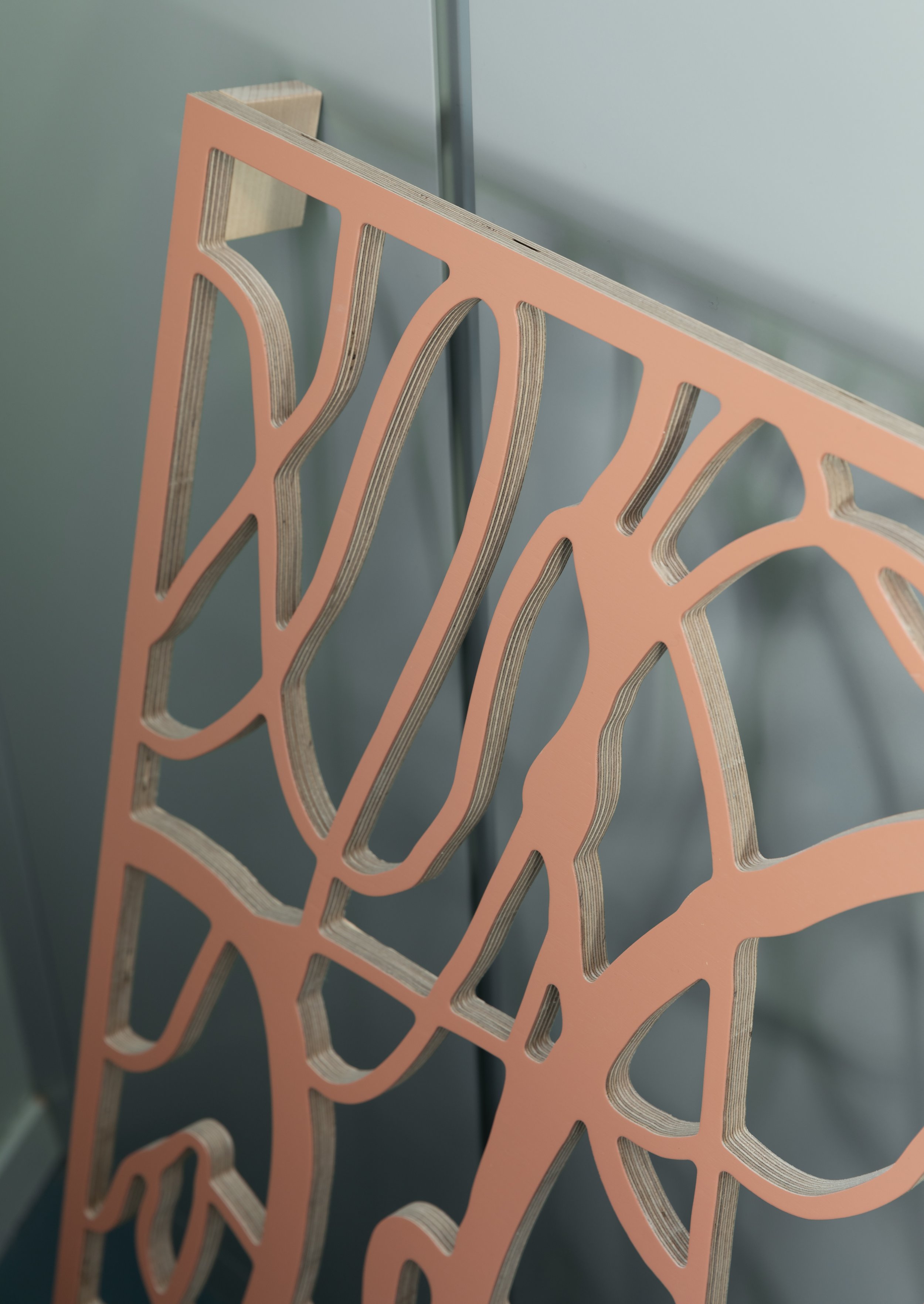 Close-up of orange layered cutout structures resembling abstract organic or biological shapes, set against a gray background.