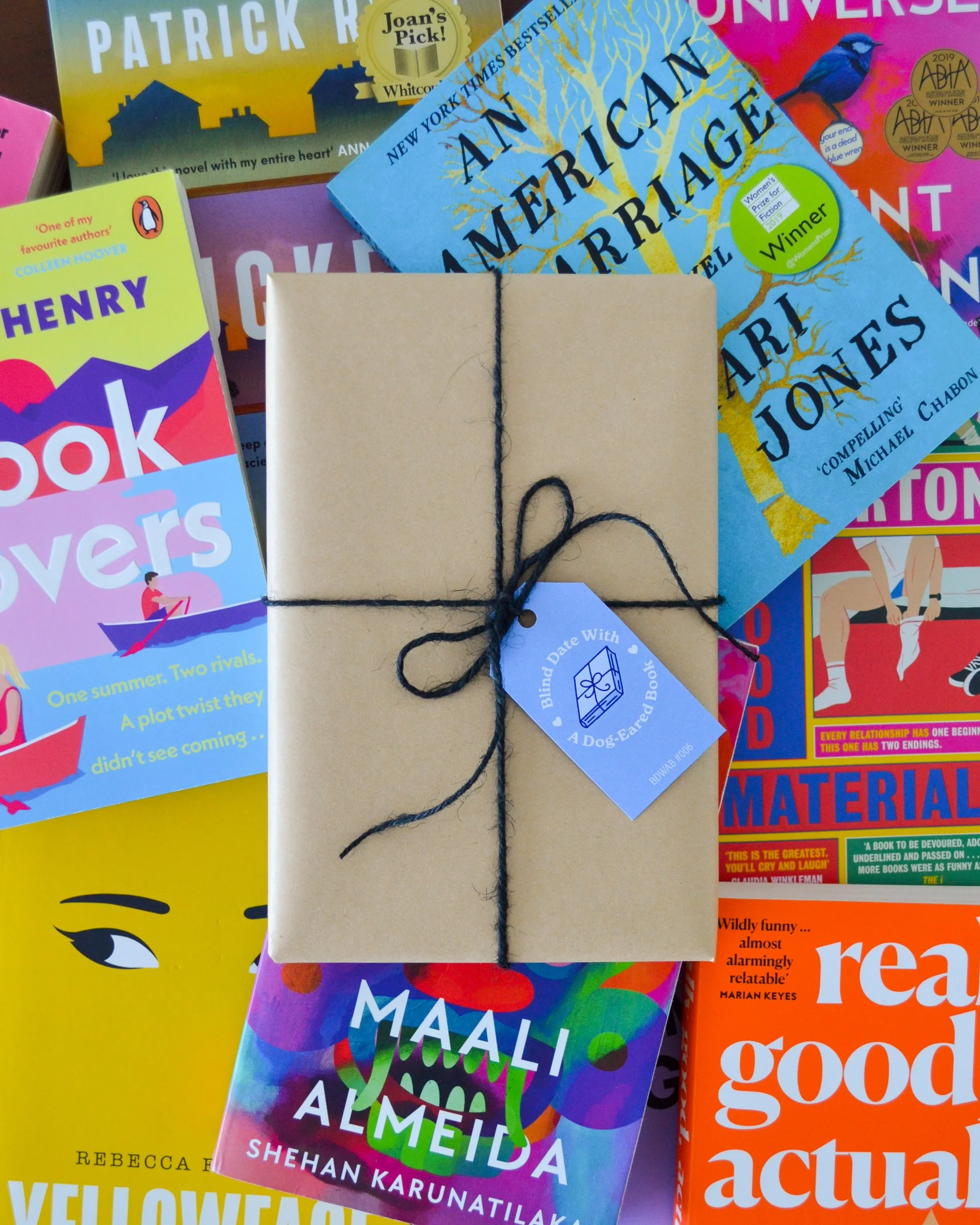 Photograph of a wrapped Blind Date With a Book on top of a pile of colourful books