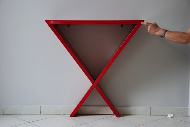 Table rouge en forme de triangle inversé avec une personne tenant une des extrémités.