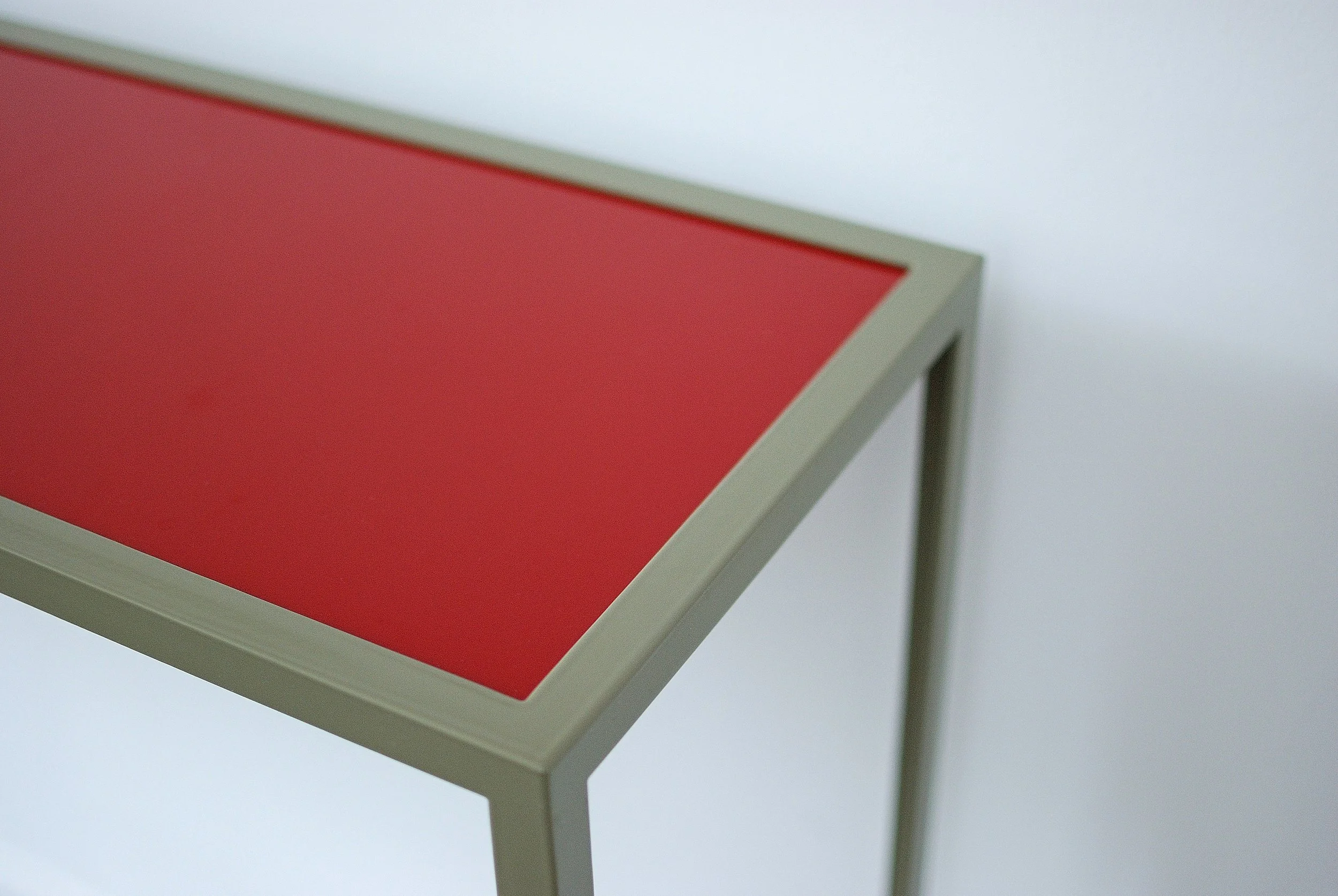 Une table moderne avec un dessus rouge et une structure blanche, placée dans un environnement minimaliste.