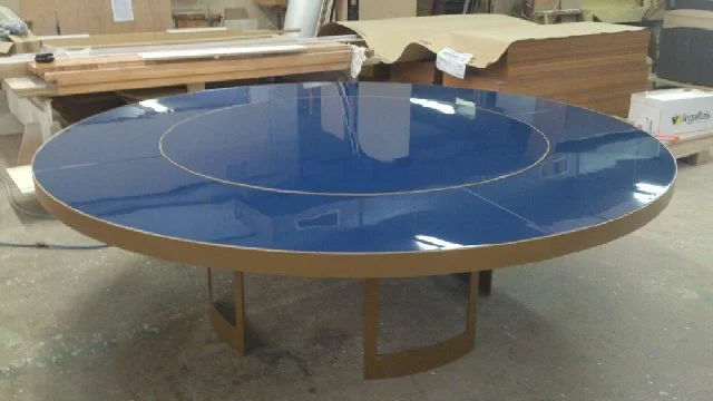 Table ronde avec un dessus en verre bleu foncé et un cadre en bois dans un atelier.