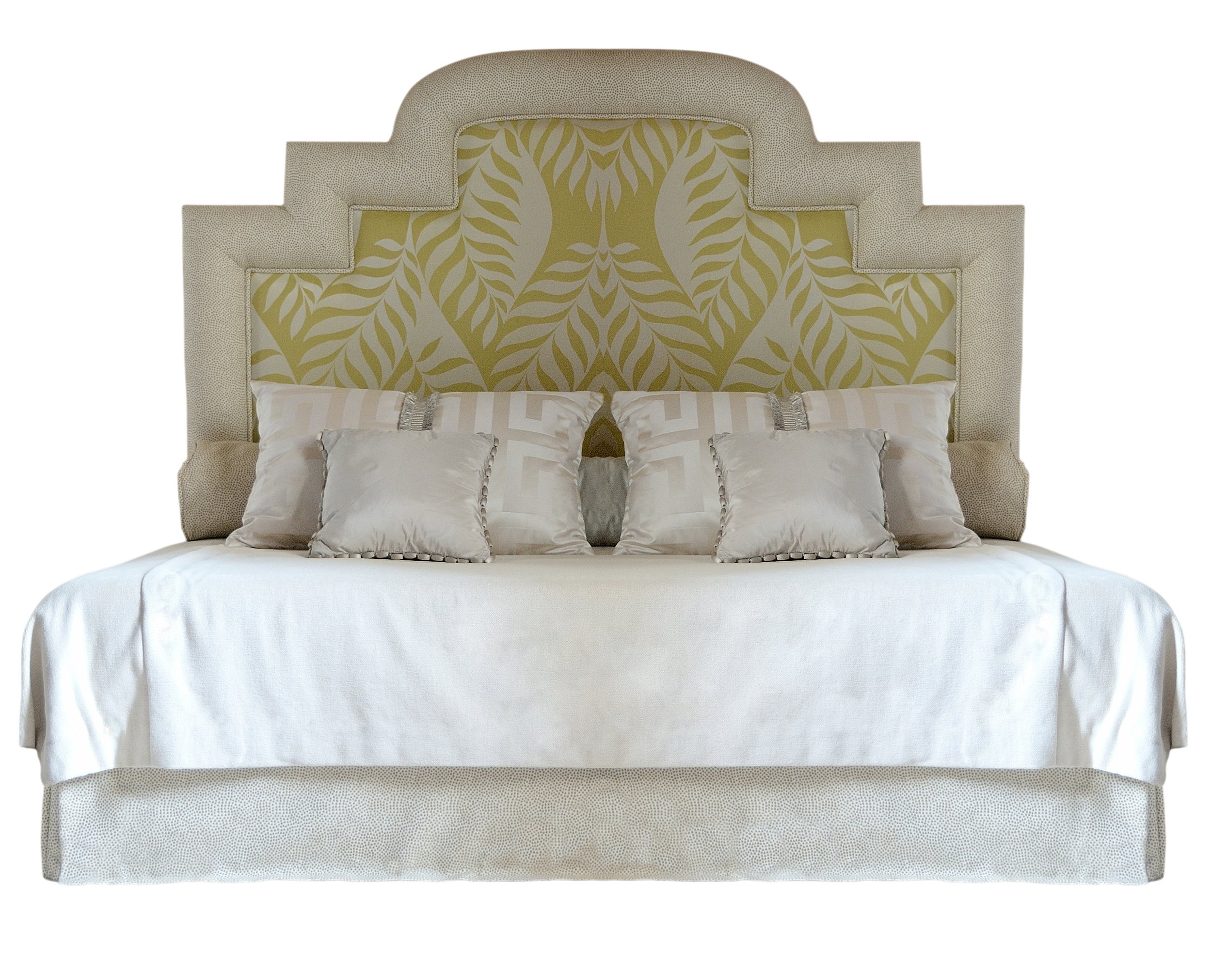 Un lit avec une tête de lit rembourrée, ornée d'un panneau en tissu avec un motif végétal en couleurs jaunes et vertes, des oreillers blancs en satin et une couverture blanche.