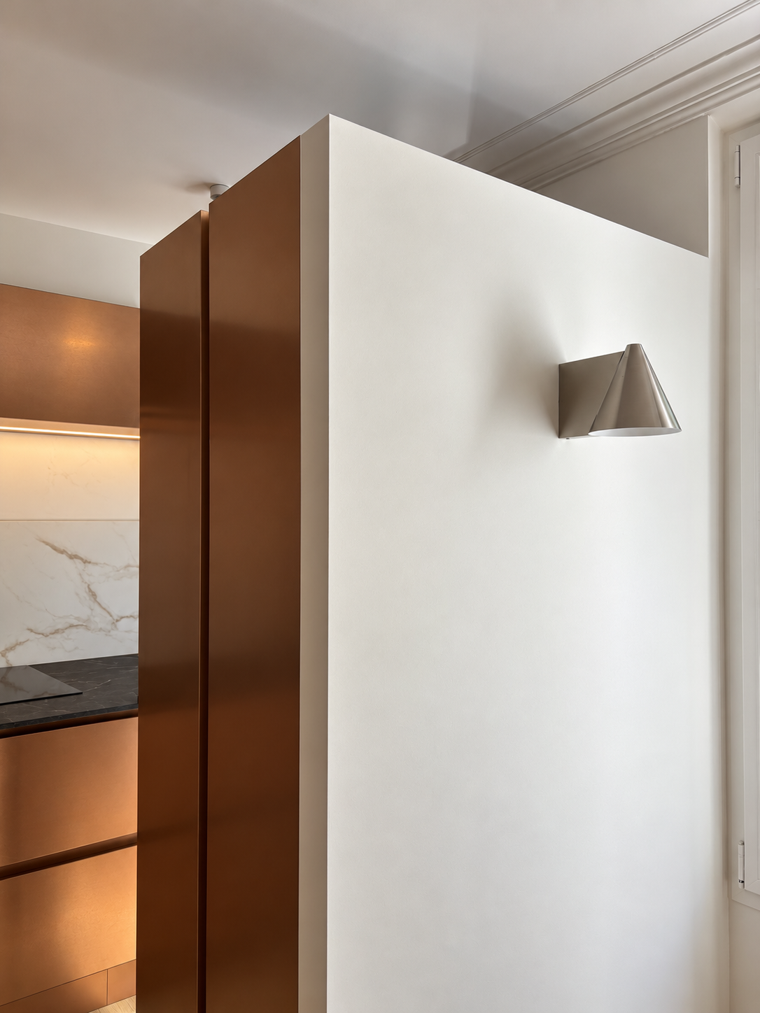 Séparation entre le salon et la cuisine : pose d'une cloison, éclairage moderne, placards réalisés sur-mesure avec façades en cuivre. 