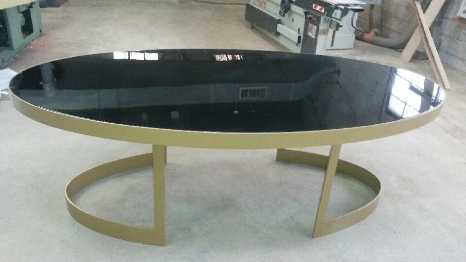 Table ovale moderne avec surface noire brillante et cadre or