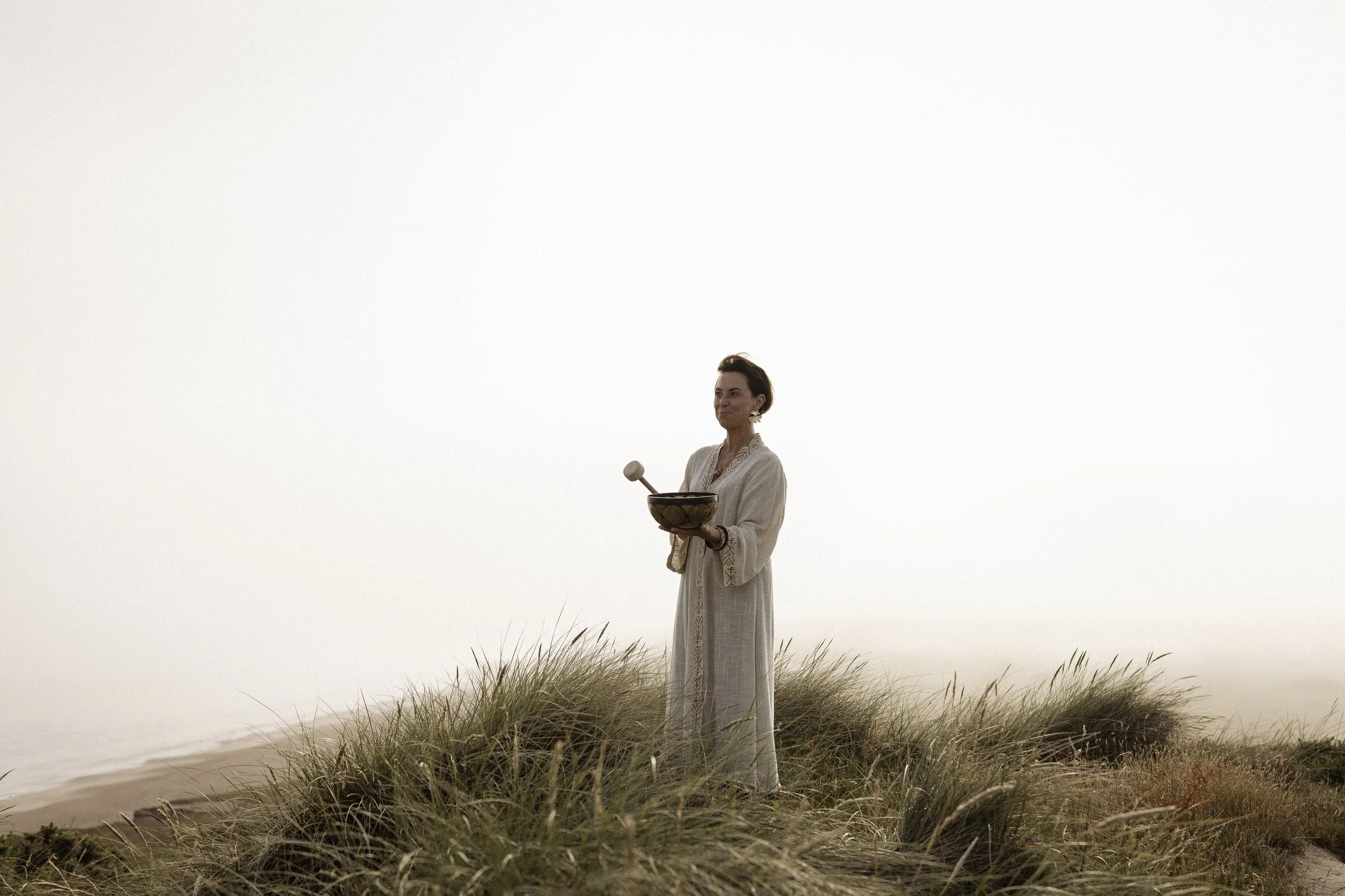 Lou Buck holding a soundbowl on the beach in Dorset.