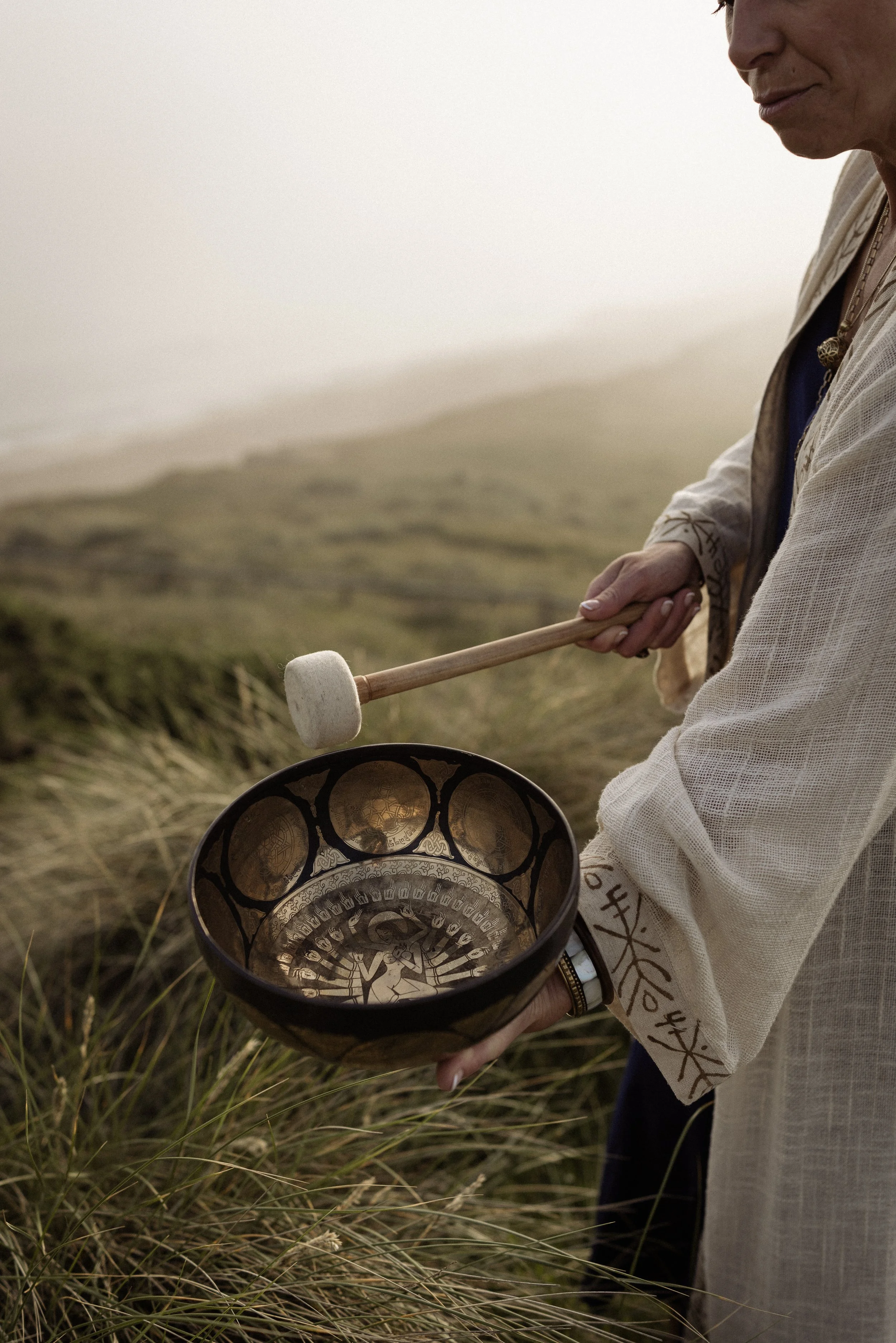 Lou Buck using a soundbowl on the beach in Dorset.