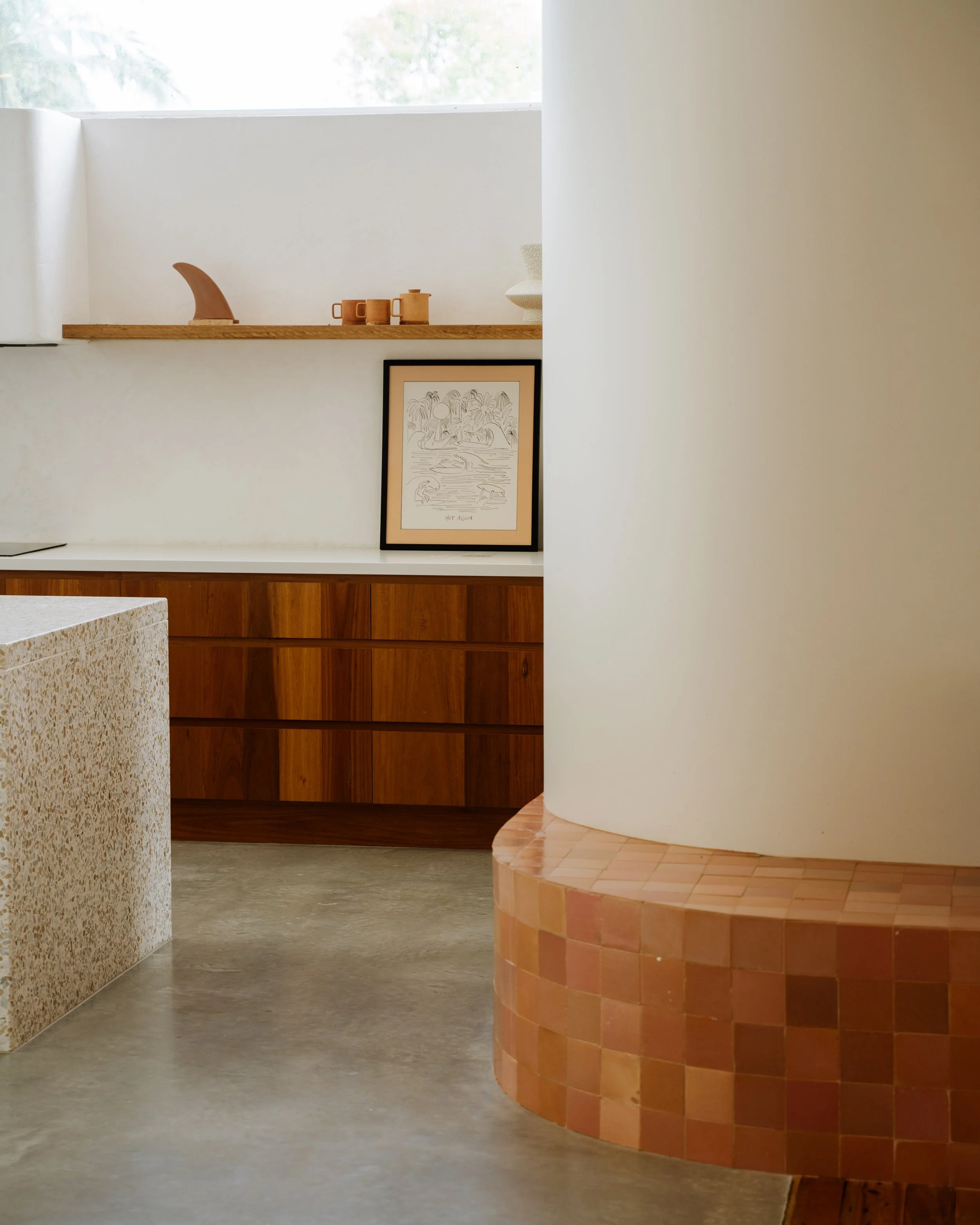 Kitchen in One Palm Building’s Kingy House renovation, featuring a curved wall, pink tiled built-in bench seat, timber shelving and natural light