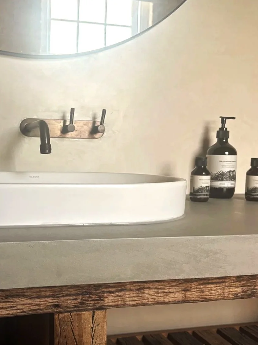 Bathroom countertop with a white ceramic sink and black faucet, three decorative black and white bottles, and a large mirror above the sink.