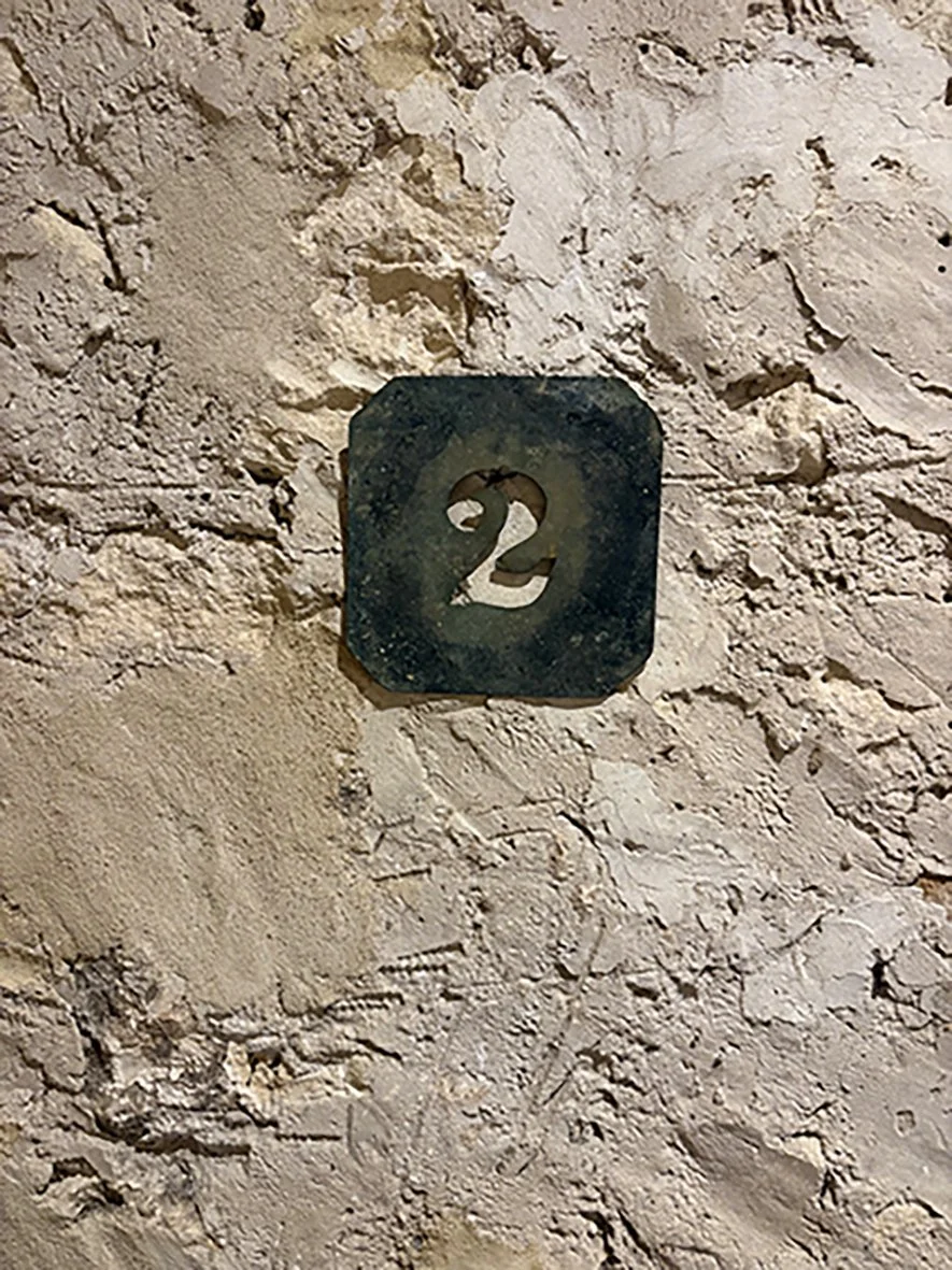 Number 2 sign on a textured stone wall.