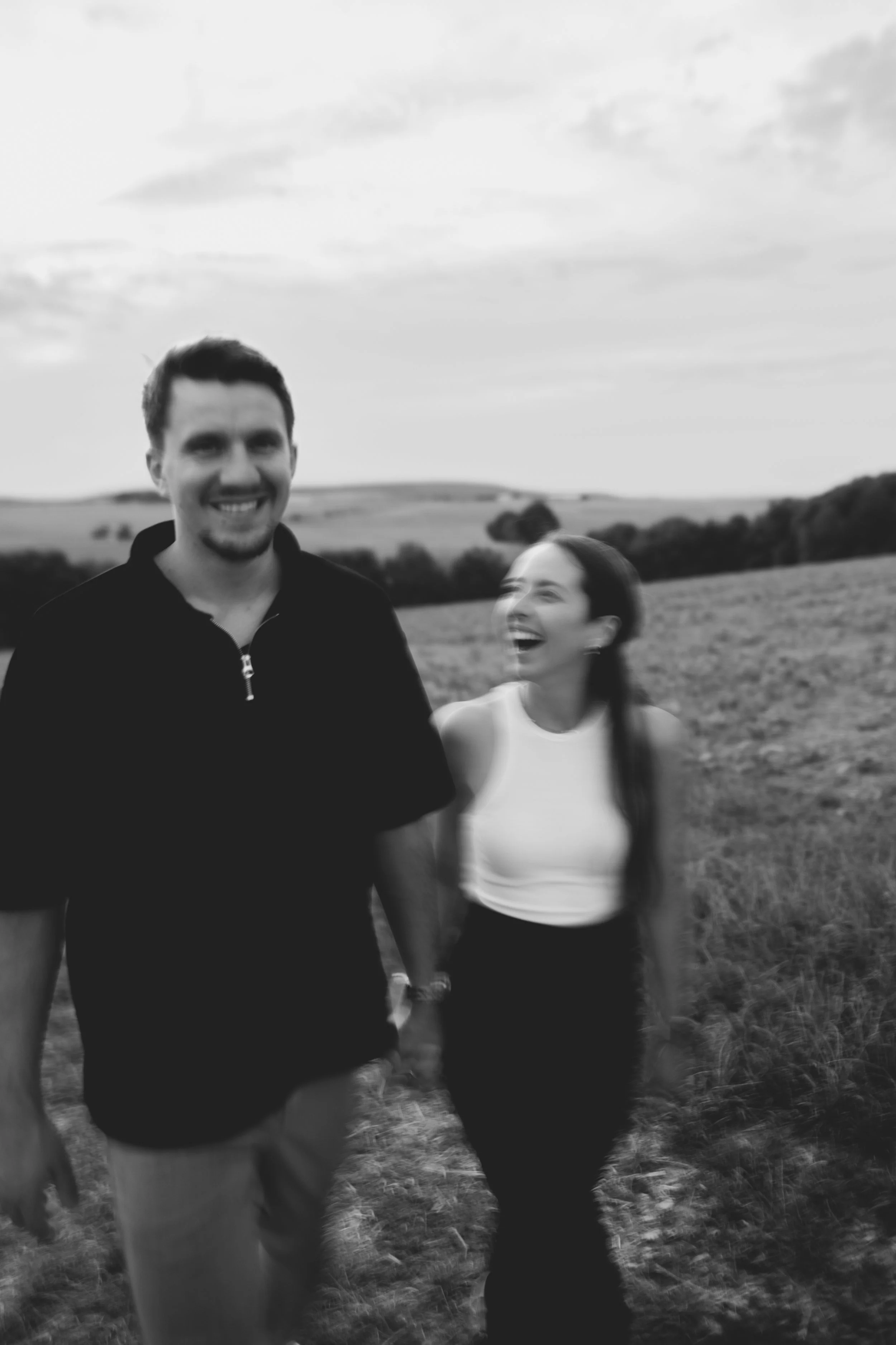 schwarz weiss Foto, dass leicht verschwommen ist, er guckt in die Kamera und sie guckt ihn an und beide lachen