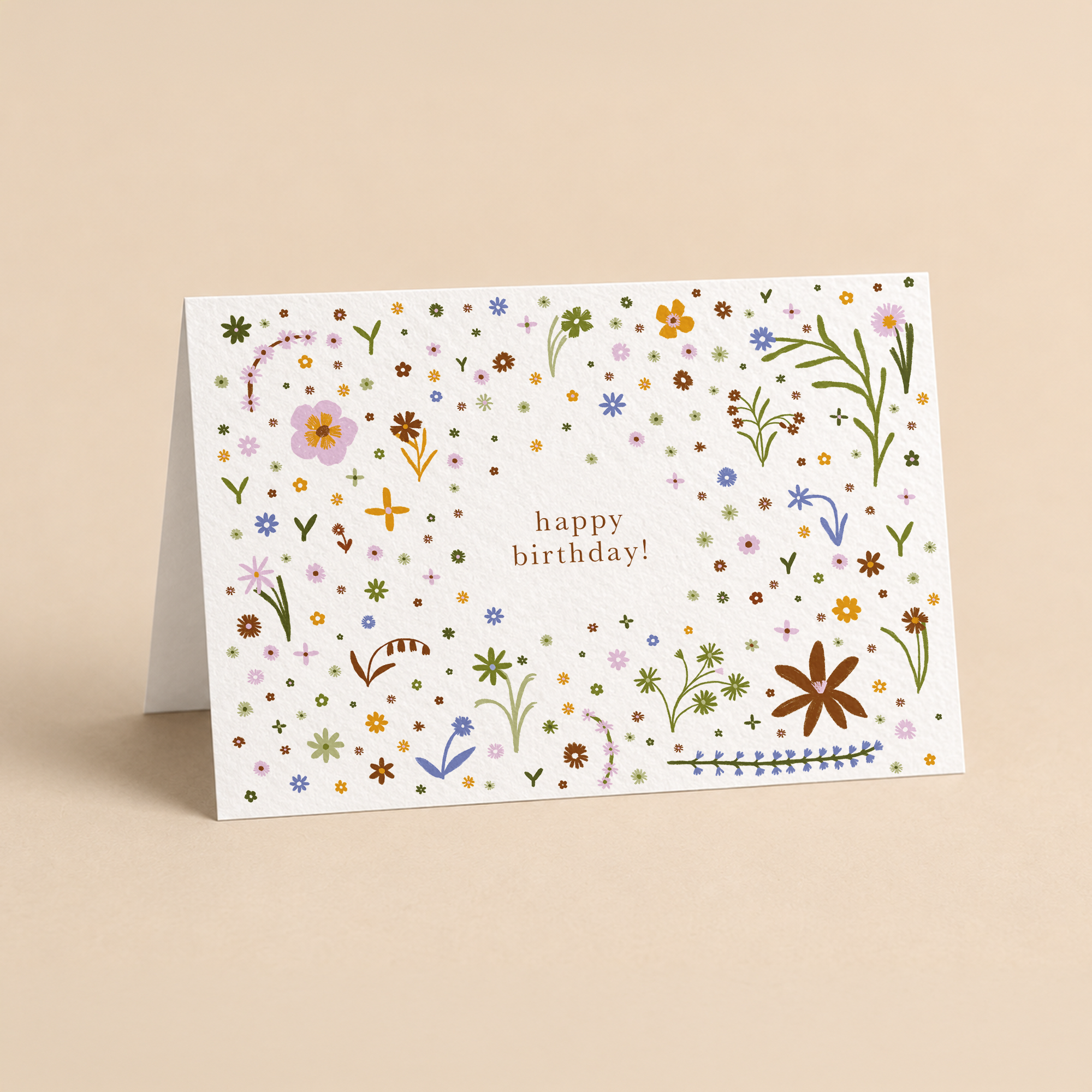 Landscape greeting card featuring a delicate confetti pattern of colorful wildflowers and the text happy birthday, original botanical illustration by Kadna Anda
