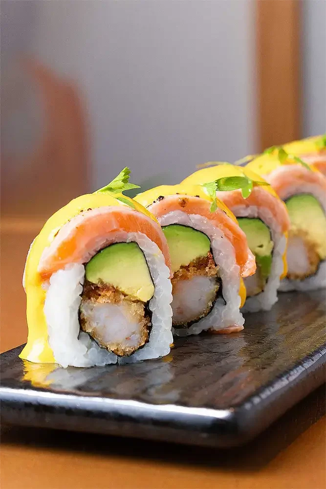 Rollos de sushi con aguacate y salmón en un plato negro