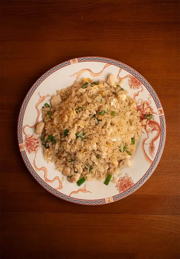 Plato de arroz frito con trozos de pollo y cebolla verde