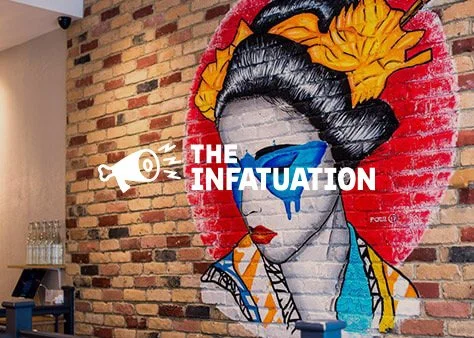 Graffiti mural of a woman with traditional in Mexican attire, with flowers in her hair and sunglasses, on a brick wall