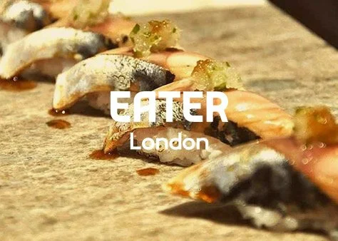 Close-up of sushi rolls with fish, rice, and sauce on a wooden surface, with overlay text 'EATER London'.