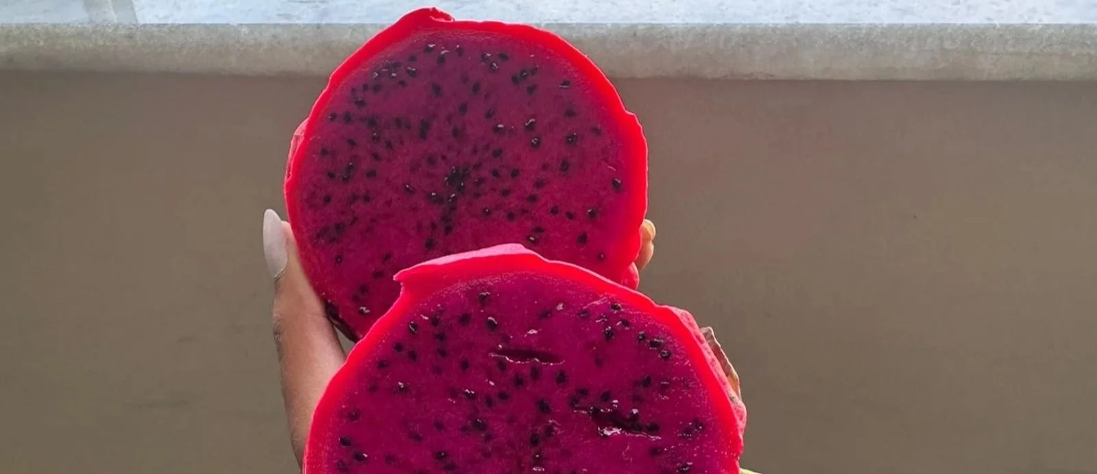 red flesh and red skin pitaya cut in two halves and held by a hand