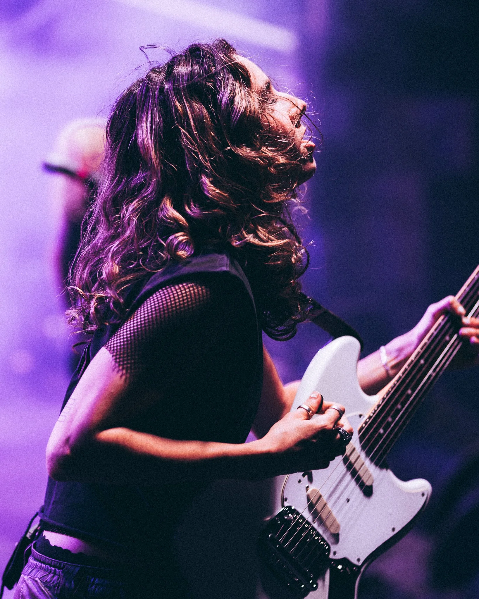 A person with long, curly hair playing an electric guitar.