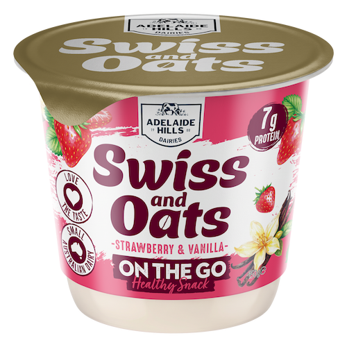 Container of Adelaide Hills Swiss and Oats strawberry and vanilla flavored snack with strawberries, vanilla flower, and spoon on pink background.