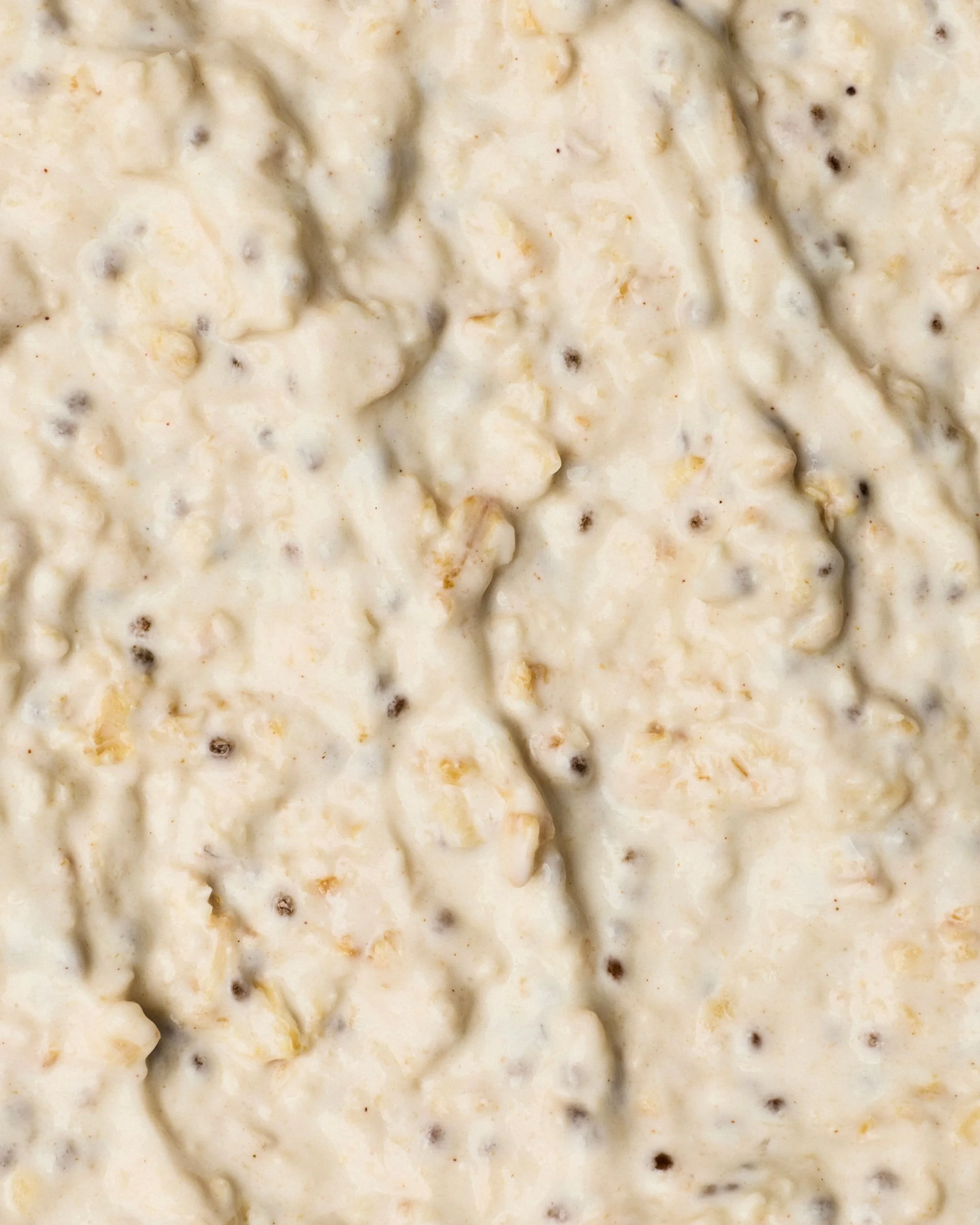 Close-up of a creamy dish with small dark specks, possibly chicken and stuffing in a casserole or baked dish.
