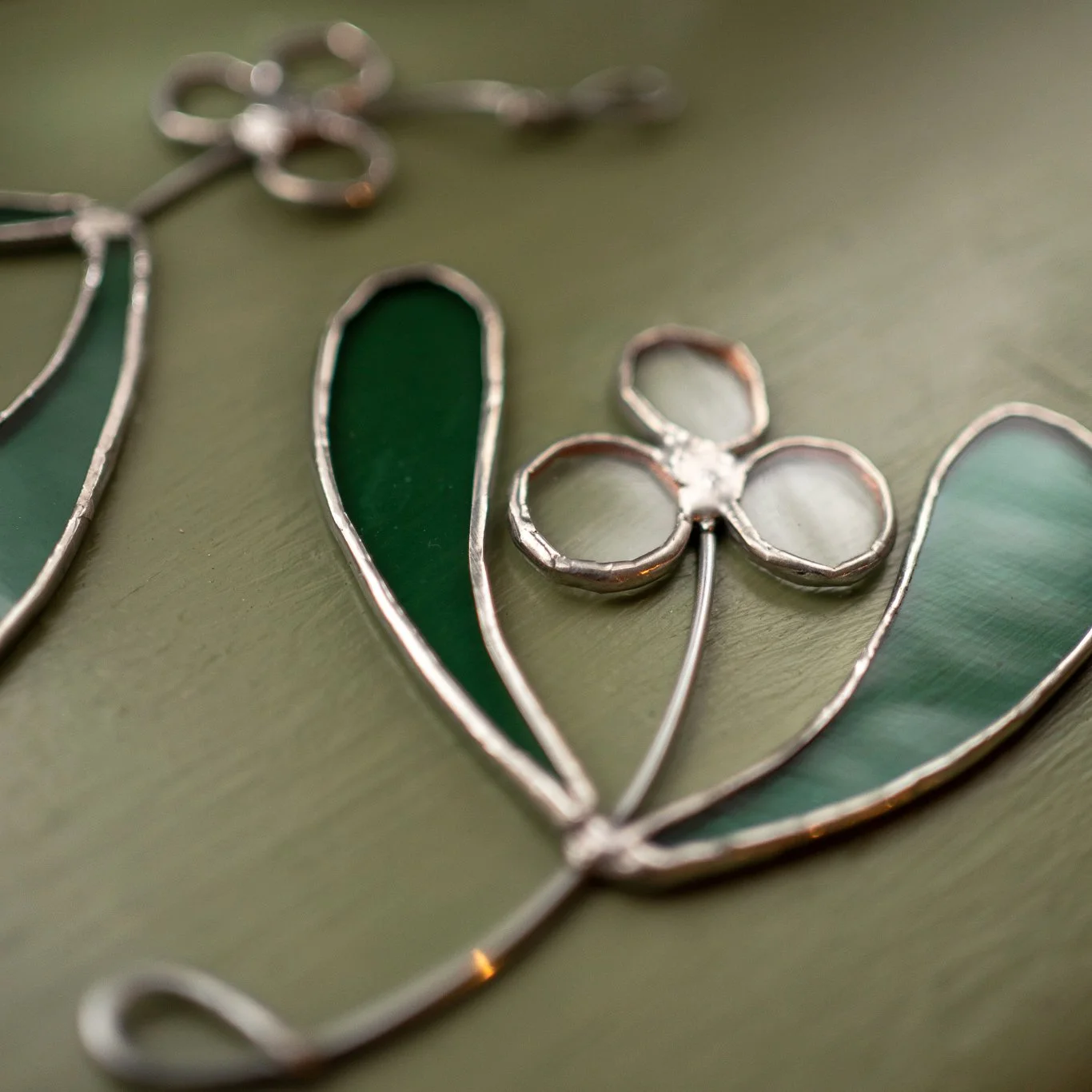 Close-up of stained glass artwork with green and clear glass sections in a floral design.