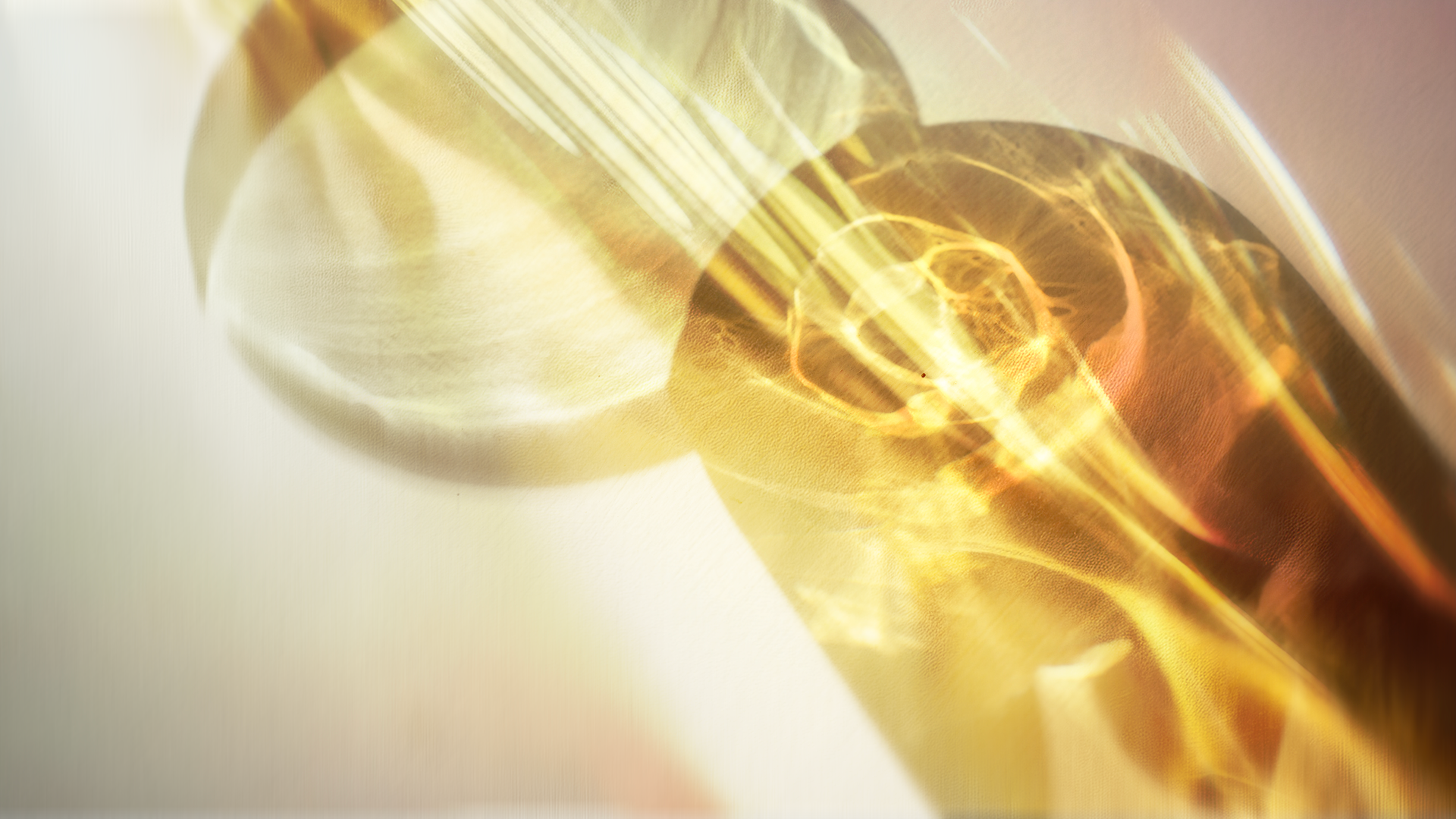 Close-up of a rolled-up translucent yellowish material with reflections and bright light streaks, creating an abstract and glowing appearance.