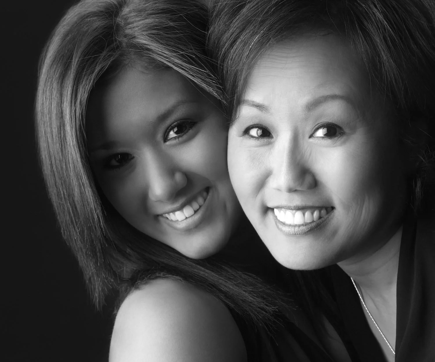Two smiling women with their faces pressed together, close black and white portrait