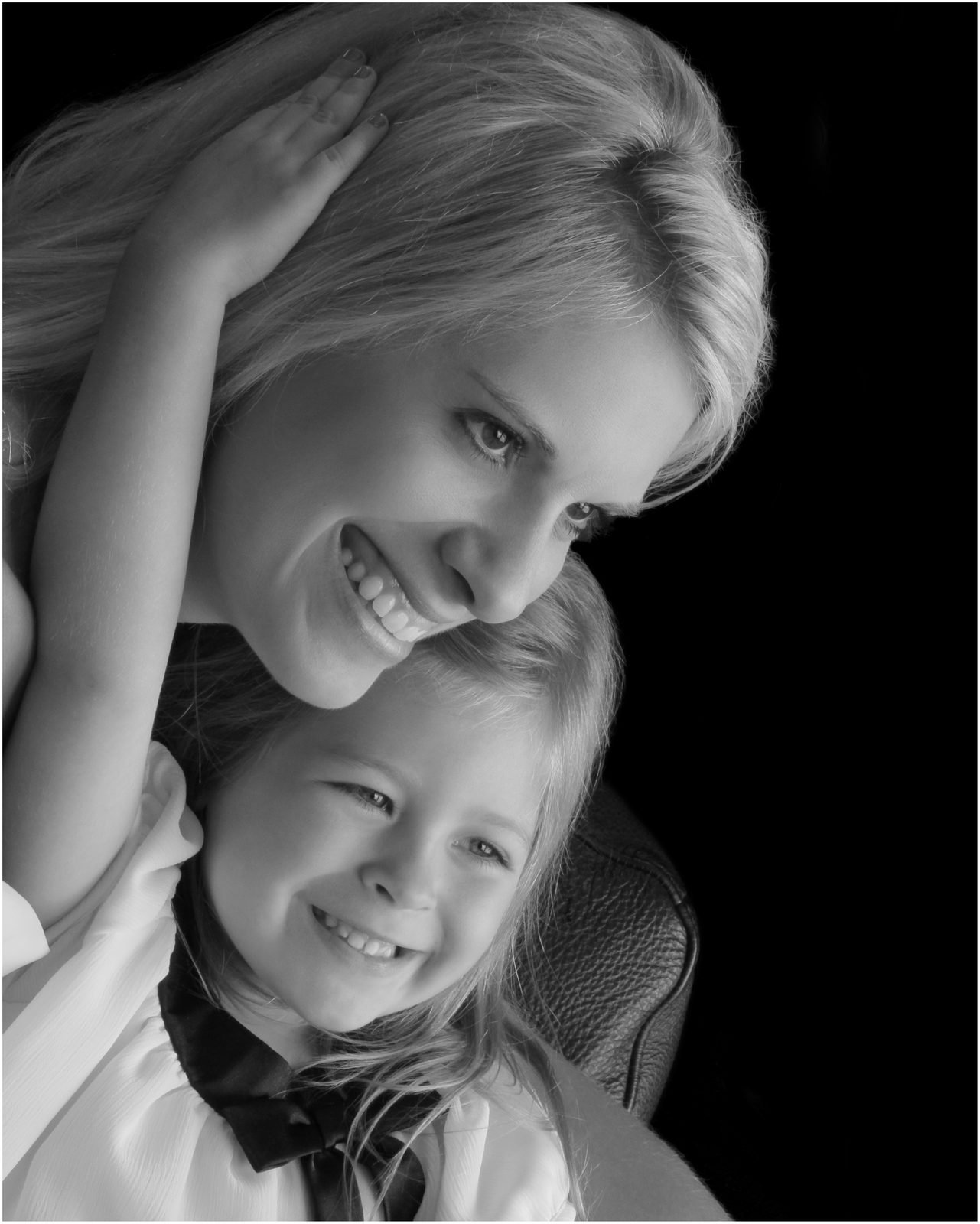 Mother and young daughter smiling together, close black and white family portrait